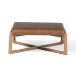 Front view of ottoman emphasizing wooden cross base supporting leather cushion