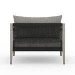 Back view showing chair’s black woven rope panel between weathered grey teak frame