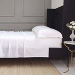 Standard white cotton percale pillowcase set with delicate ruffled edges on a black bed frame.