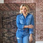 Woman standing in front of two rugs hanging on wall, one matching Southwestern tribal pattern