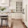 Jules Tangerine / Mist rug runner styled in bright kitchen with white cabinetry and black bar stool on hardwood.