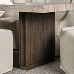 Side view of the block leg vertical ridged wood design with lightly textured area rug and beige chairs