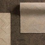 Overhead shot of two folded rugs stacked, highlighting the Friesian rug's pattern compared to a contrasting dark geometric...