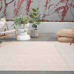 Cream indoor-outdoor rug styled on outdoor floor with modern planters and woven cushions