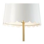 Close-up of white scalloped lamp shade with gold interior and brass support visible