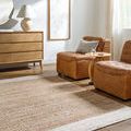 Kamey Sandstone Rug styled in a bright living room with tan leather chairs and wooden floor