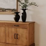 Closer room angle showing texture of wood and details of two black vases with leafy branches