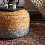 Textured woven ottoman in golden brown and gray sitting on the rust and gray patterned area rug