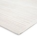 Close-up on soft high-low textured bark pattern and edge of white and ivory modern area rug