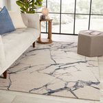 Rug styled in modern living room with beige sofa, blue pillow, side table, and natural light