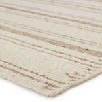 Close-up angled view showing thick wool texture and tightly finished edge binding in cream and brown