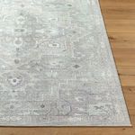 Close-up corner view highlighting subtle border design and low-medium pile texture on dusty sage rug