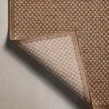 Back view of the rug folded to reveal non-slip woven backing in beige tones
