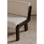 Close-up of chair leg and frame showing wood grain detail and upholstery edge near seat corner