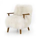 Three-quarter view showing armchair angled to reveal sculpted wooden arms and dense fur upholstery