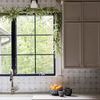 Wide kitchen view highlighting two grey daisy planters on countertop with backsplash tile and black-framed window