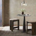 Stool in neutral-toned room beside round pedestal table with flower vase