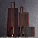 Three Yami Brown bread boards of different sizes arranged against a textured backdrop with wooden utensils