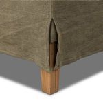 Close-up detail showing chair skirt slit revealing solid oak leg beneath linen fabric