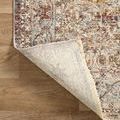 Rug corner folded to show backside texture and fringe detail on light wood flooring
