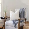 Similar styled recliner with gray blanket and white textured pillow in light-filled living space