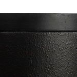 Detail of textured black metal base surface and joinery to tabletop