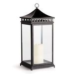 Tall black outdoor lantern with wide sweeping top and clear glass panes showing a white candle inside