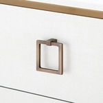 Square brass drawer pull detail against white textured linen drawer front