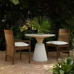 Pair of Savannah arm chairs in dark finish with white cushions, styled outdoors with round white pedestal table
