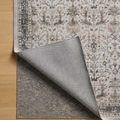 Rug corner folded back exposing a layered gray rug pad underneath