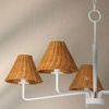 Three-light Issa chandelier with white arms and natural woven rattan shades on beige wall