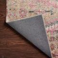 Rug corner flipped over exposing solid gray backing and stitched edging on hardwood floor