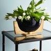 Top view of Conner Cane End Table showcasing the glass shelf with white tulips in a black and gold vase
