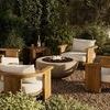 Wider angle of fire table with flames, showing the outdoor seating arrangement and natural wood furniture