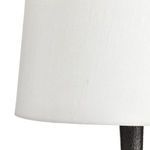 Close-up of lower edge of white fabric shade and textured black lamp base
