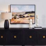 Desert Moment art displayed above a black sideboard with lamp and white ceramic candleholders