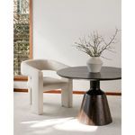 Elo Chair positioned beside round dark wood table with white vase in sunlit modern room