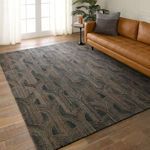 Rug placed in living room with leather sofa, hardwood floor, natural light from glass doors, styled with throw pillow and ...