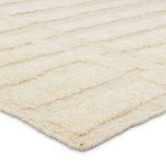 Close angle of cream wool rug's edge displaying thick pile and textured stripes