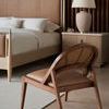 Leather and wood contemporary chair angled near the bed with slat wall and nightstand in soft focus