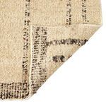 Rug corner flipped over revealing woven wool texture and pattern on the underside