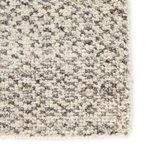 Tight close-up showing plush wool fibers and geometric motif in dark gray on ivory background