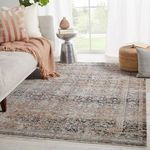 Living room scene with Elio Oriental Gray Black rug near sofa with orange and cream pillows