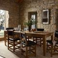 Penny Gold/Natural Rug under dining table in rustic stone-walled room with wooden chairs and natural light