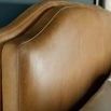 Close-up of caramel leather headboard stitching and texture with pillow cushions in foreground