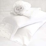 Stack of white bamboo pillowcases with fitted sheet rolled on top, showing fabric smoothness