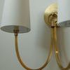 Close-up of sconce fabric shade and brass arm from front angle
