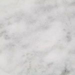 Detailed zoom on white marble surface showing smooth finish and soft gray veining pattern