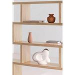 Partial close-up of shelf styling showing books, terracotta vases, and abstract white sculpture