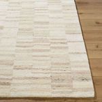 Detailed corner shot of the Max Sandstone rug showing edge finish and soft wool pile on a wooden floor.